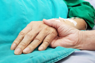 Oncologist doctor holding patient's hand in hospital. Showing all love, empathy, helping and encouragement. He has end stage cancer disease. Healthcare in end of life and palliative care concept
