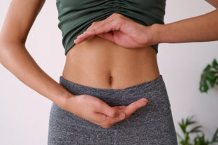 Close up of a young multi ethnic woman's stomach cupped by her hands