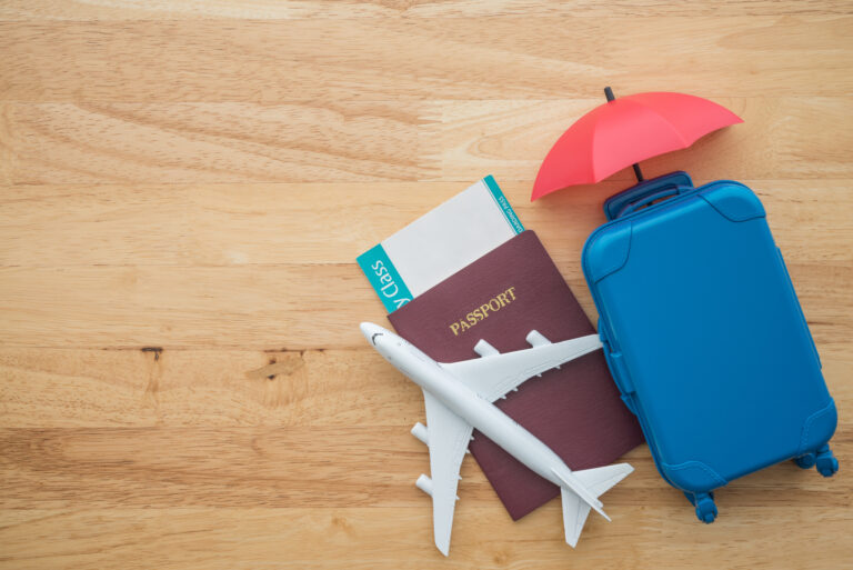 Red umbrella cover airplane, passport, flight tickets and suitcases travelers on wooden background.