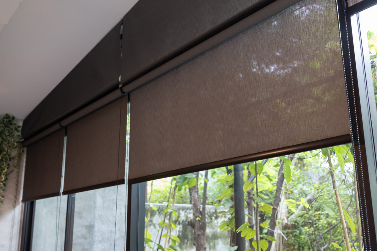 A window with a black blind curtain that is hanging down.