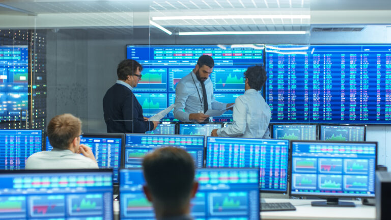 Three Experienced Stock Traders Talking Business, Consulting Documents and Argue About Data. They Work for a Big Stock Exchange Firm. Office is Full of Displays Showing Infographics and Numbers.
