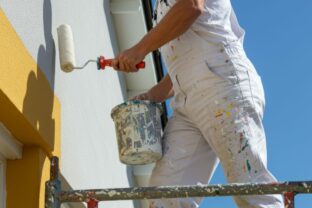 Professional house painter diligently painting the facade with roller brush