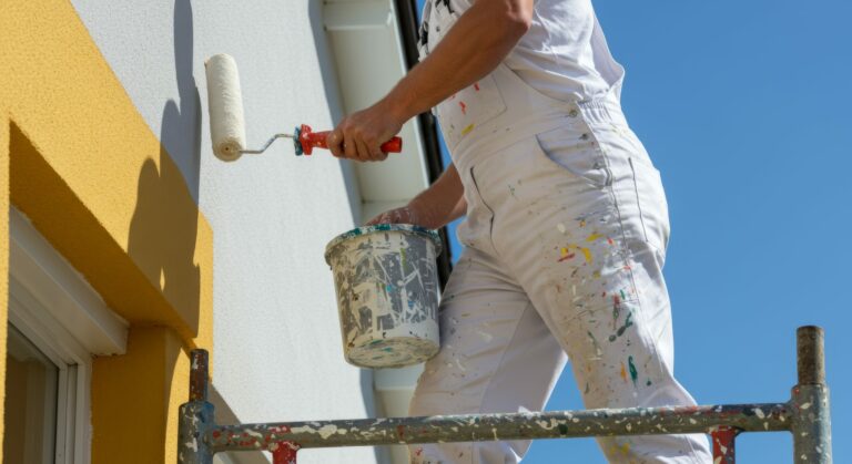 Professional house painter diligently painting the facade with roller brush