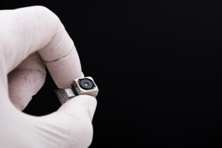 Small spy camera in hand concept on black background