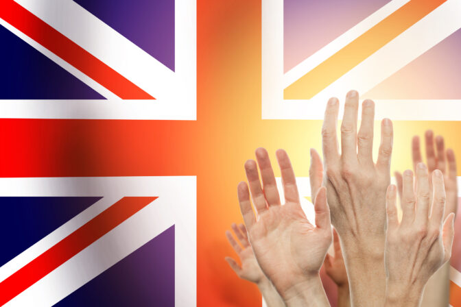 People raising hands and United Kingdom flag on background. Patriotic concept