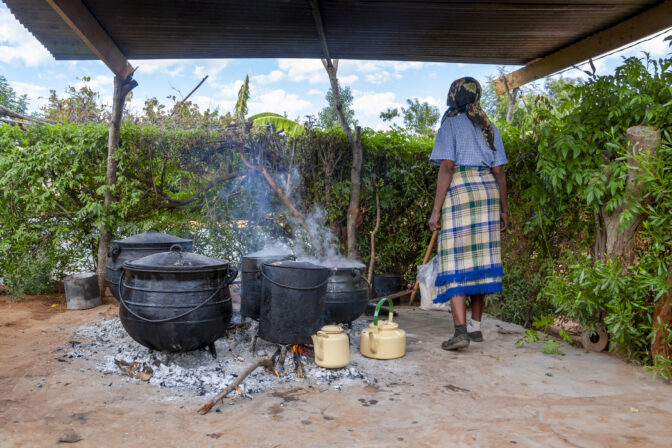 African woman, cooking in few Big pots outdoors