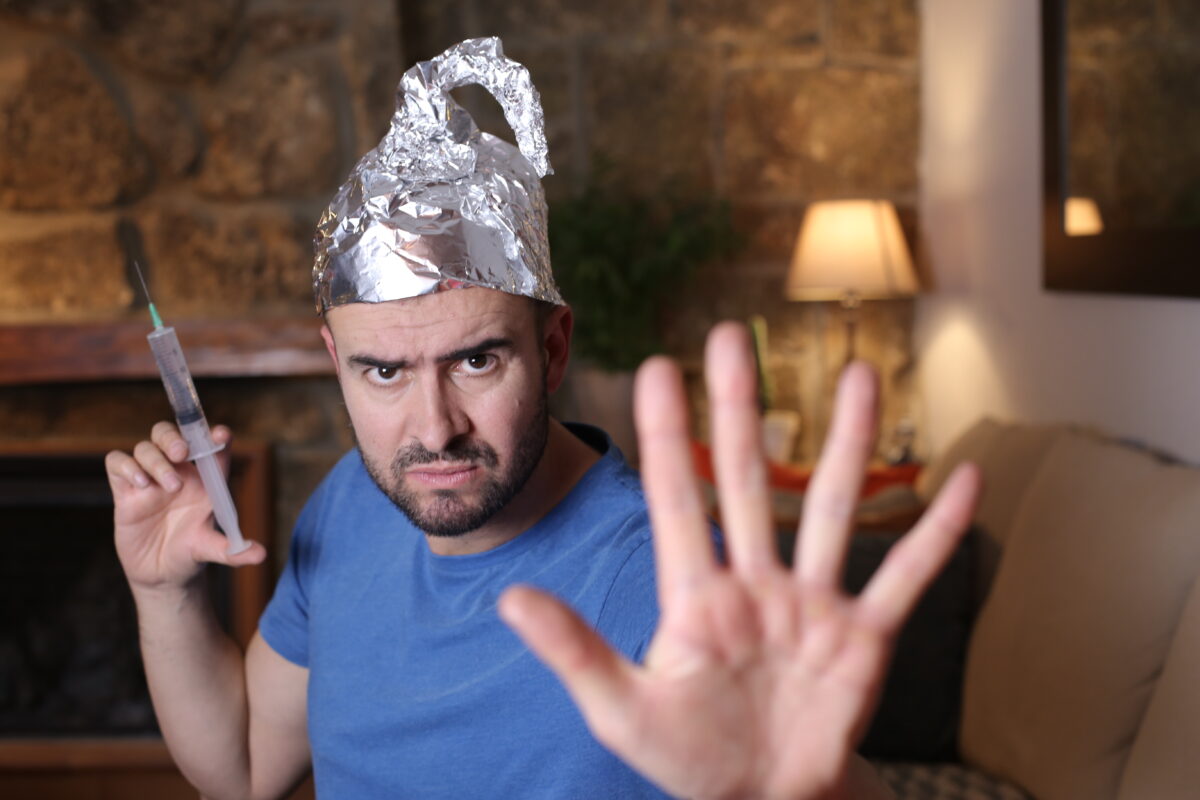 Man wearing tin foil hat holding syringe