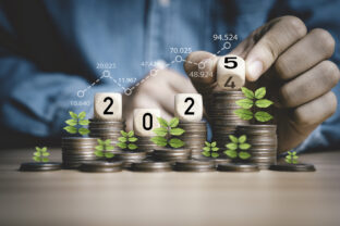 Businessman hand flipping wooden block cube from 2024 to 2025 on coins stacking for business budget planing and investment growth of new year con