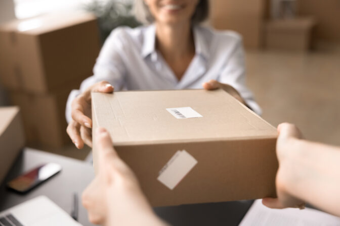 Seller handling parcel box to recipient, close up cropped view