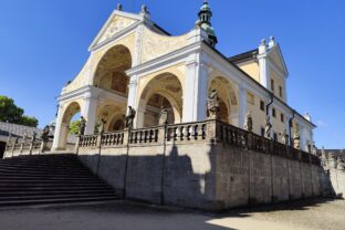 Svatá Hora - s bohato zdobenými arkádami, sochami svätcov a modrou oblohou v pozadí.