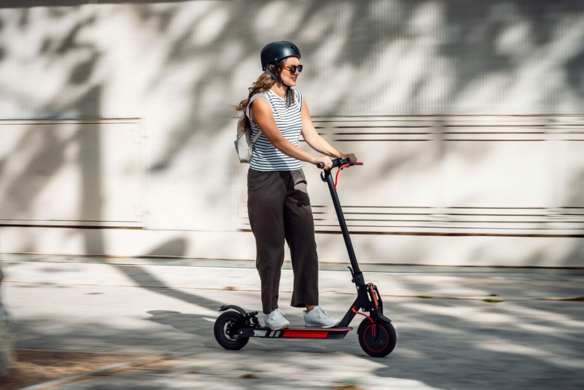 Shot,Of,Confident,Cheerful,Woman,Riding,Electric,Push,Scooter,Through
