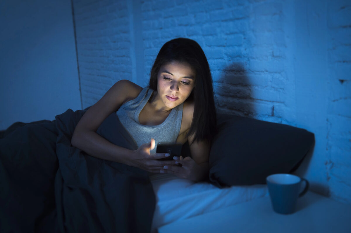 žena s mobilom v posteli