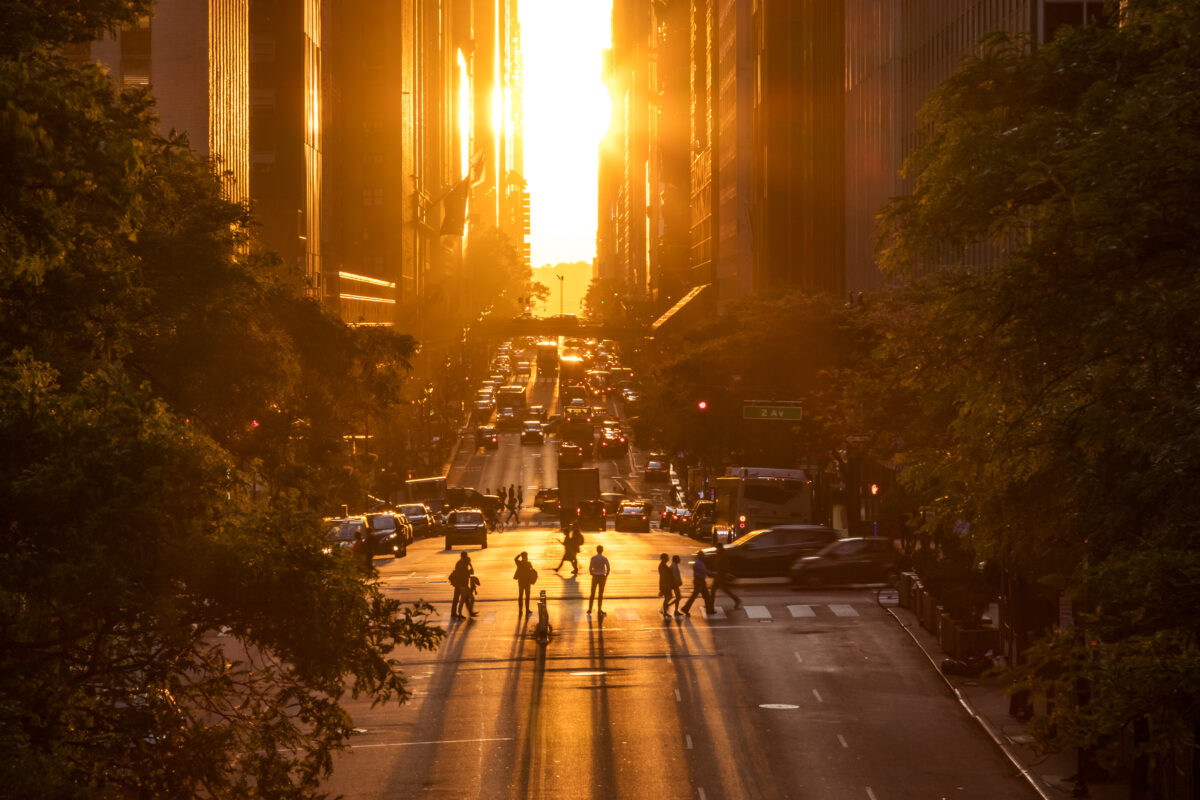 Rays of sunlight shining down on the people and traffic at the intersections along 42nd Street in New York City