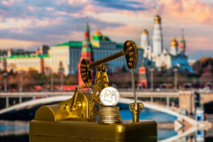 Miniature golden oil pump and coin with the symbol of the Russian ruble against the background of the Moscow Kremlin
