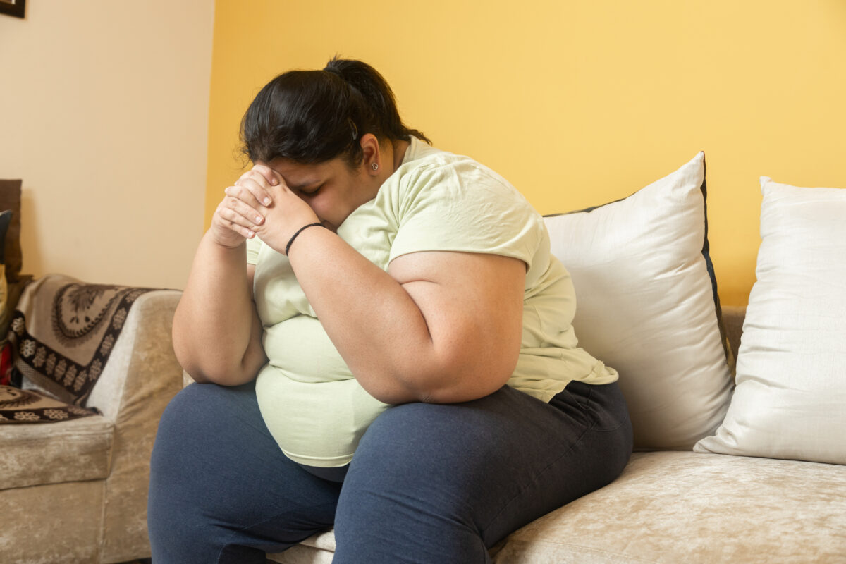 Mental health Depressed overweight asian indian woman sitting at home alone. Sad Plus size female sitting on couch. Fat lady weight loss and obesity problem. People of india have emotional stress, Body conscious. Loneliness