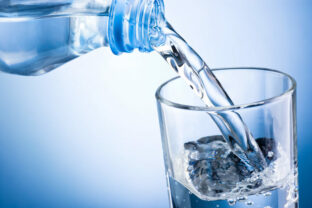 Closeup of bottle of water pouring into a glass