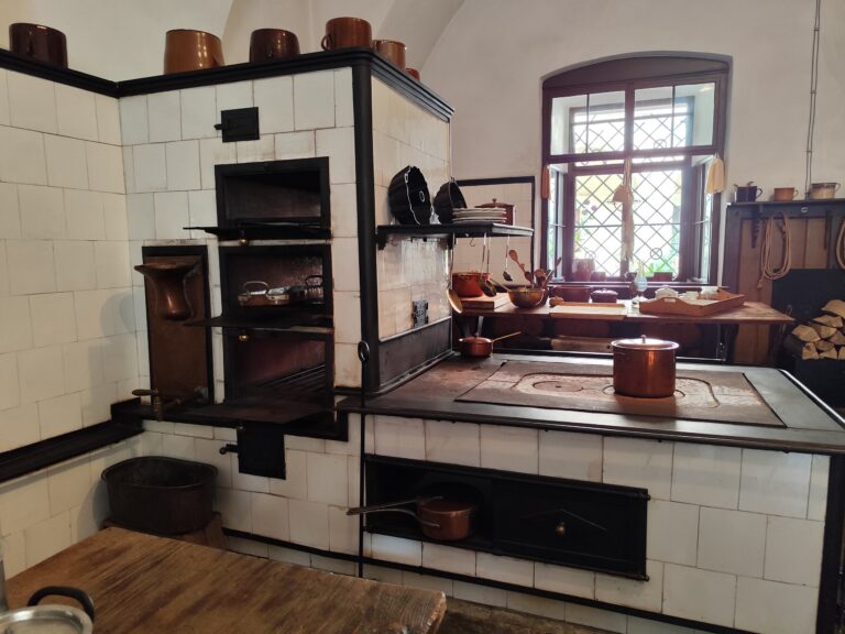 Dobová kuchyňa na Zámku Žleby, vybavená sporákom z roku 1870, je dodnes plne funkčná a každoročne sa tu pečú koláče v dobových kostýmoch, čo návštevníkom ponúka autentický zážitok z minulosti.