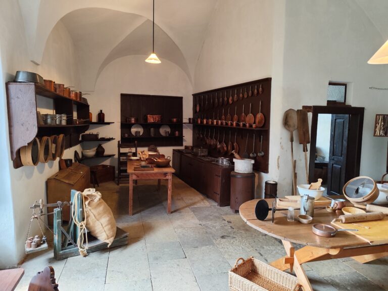 Dobová kuchyňa na Zámku Žleby, vybavená sporákom z roku 1870, je dodnes plne funkčná a každoročne sa tu pečú koláče v dobových kostýmoch, čo návštevníkom ponúka autentický zážitok z minulosti.