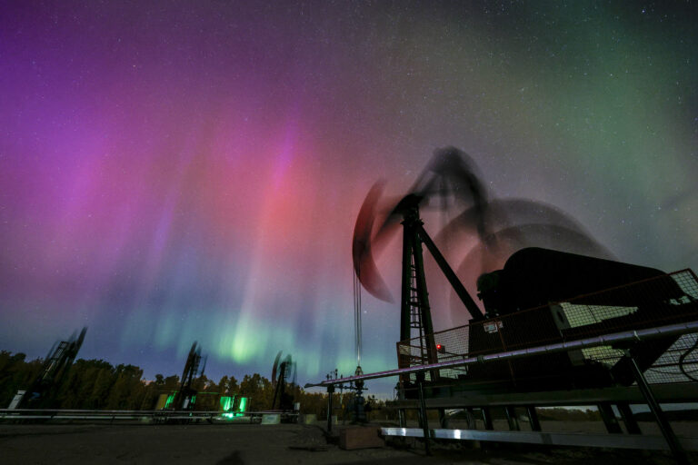 aurora borealis polárna žiara krajina hory nočná obloha mesto stromy cesta čerpacie stanice ropa plyn vrt