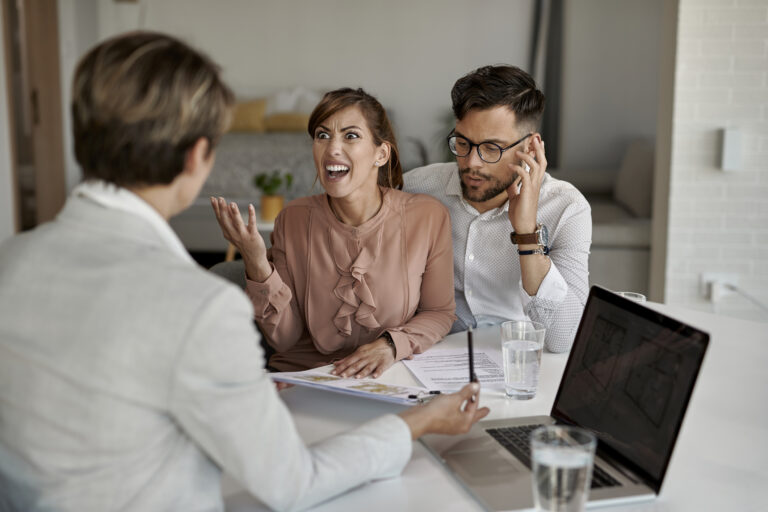 Displeased couple arguing with their real estate agent during a meeting.