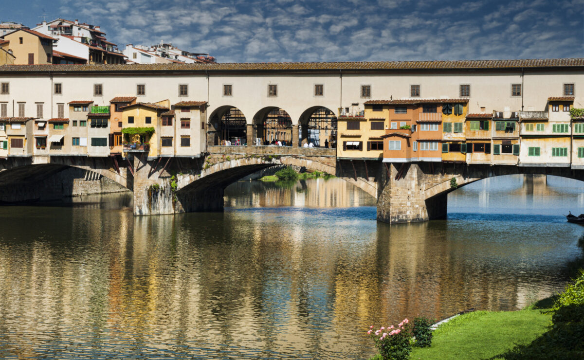 View of the Ponte Vecchio reflected in the water of the Arno river.