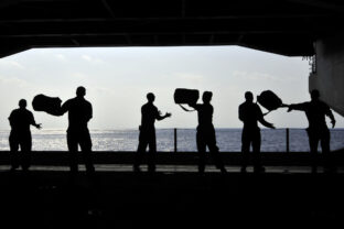 Sailors pass supplies to each other in the hangar bay of USS Ronald Reagan.