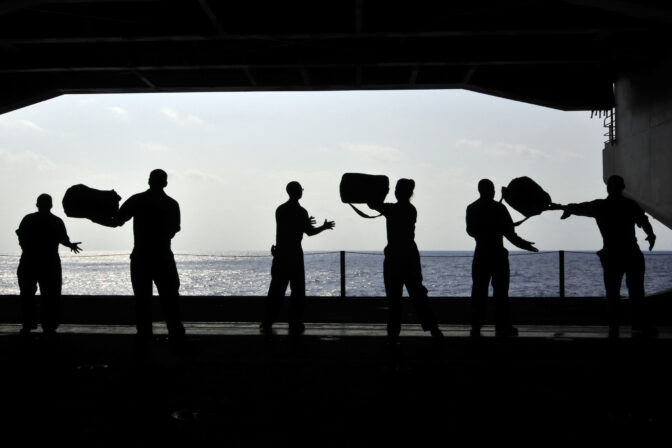 Sailors pass supplies to each other in the hangar bay of USS Ronald Reagan.
