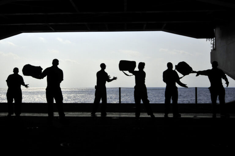 Sailors pass supplies to each other in the hangar bay of USS Ronald Reagan.