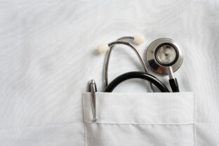 Stethoscope and pen in doctor robe pocket