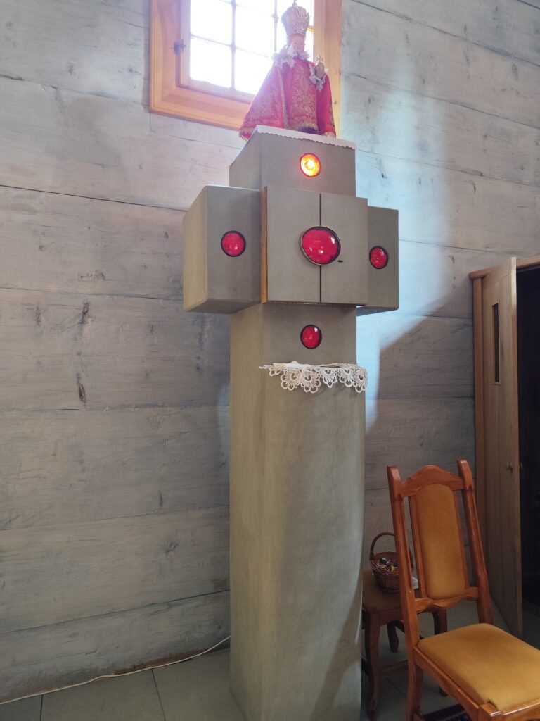 Interiér dreveného kostolíka v Gutech s oltárom, lavicami a liturgickými zástavami, replika postavená v roku 2021 po požiari pôvodnej stavby.