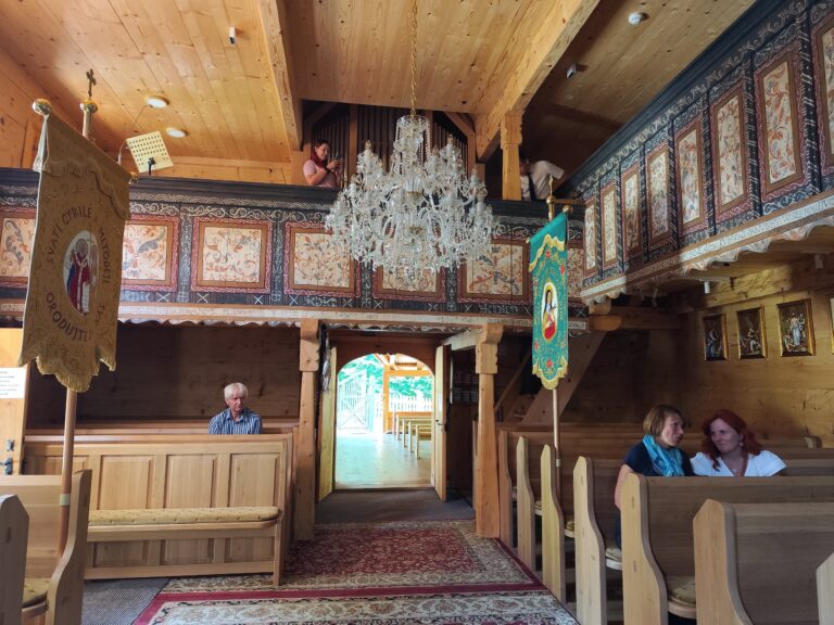 Interiér dreveného kostolíka v Gutech s oltárom, lavicami a liturgickými zástavami, replika postavená v roku 2021 po požiari pôvodnej stavby.