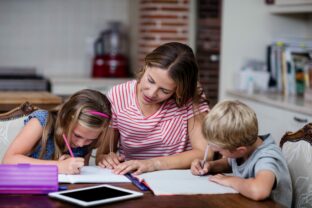 Mother,Helping,Kids,With,Their,Homework,At,Home
