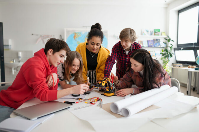 Group of students building and programming electric toys and robots at robotics classroom