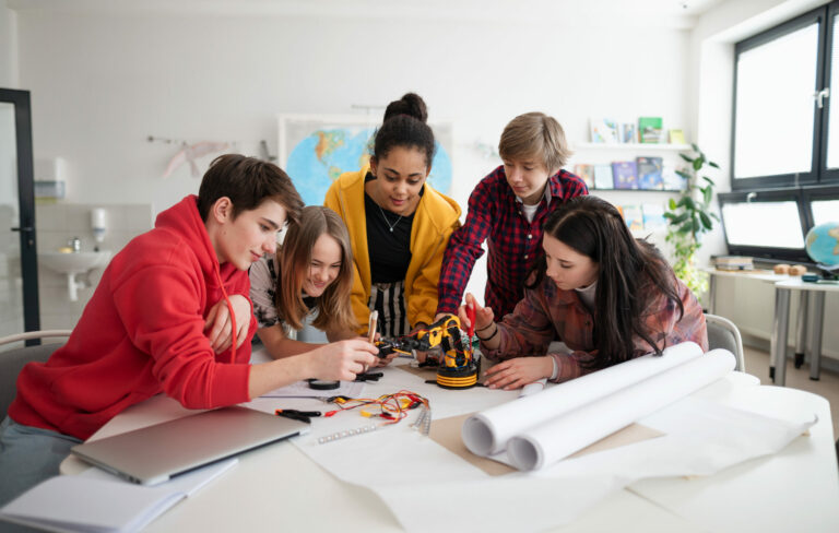 Group of students building and programming electric toys and robots at robotics classroom