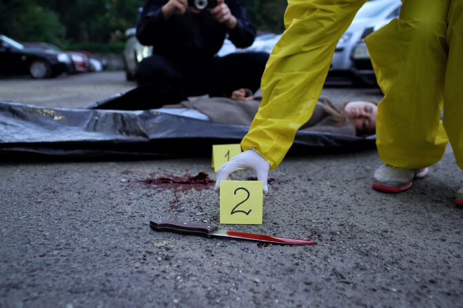 Police making photo and fixing numbers of evidence, dead body and knife on road