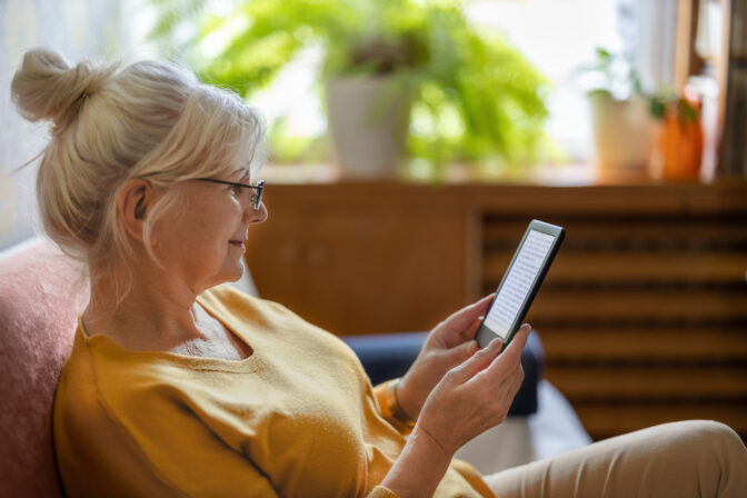 Senior woman using e reader and reading an e book at home