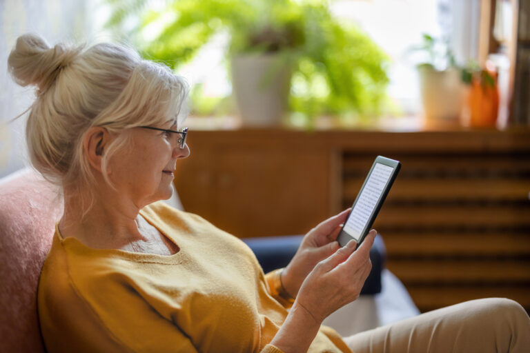 Senior woman using e reader and reading an e book at home