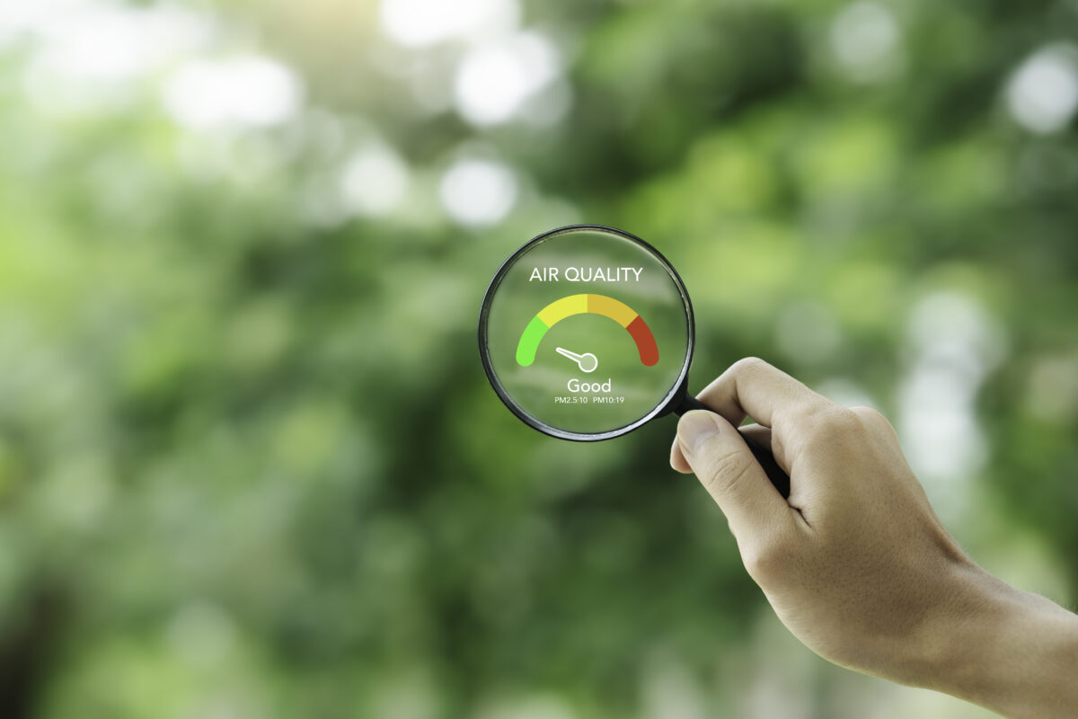 Hand holding a magnifying glass to check the  good air quality and clean outdoor air quality safe from pollution dust PM 2.5