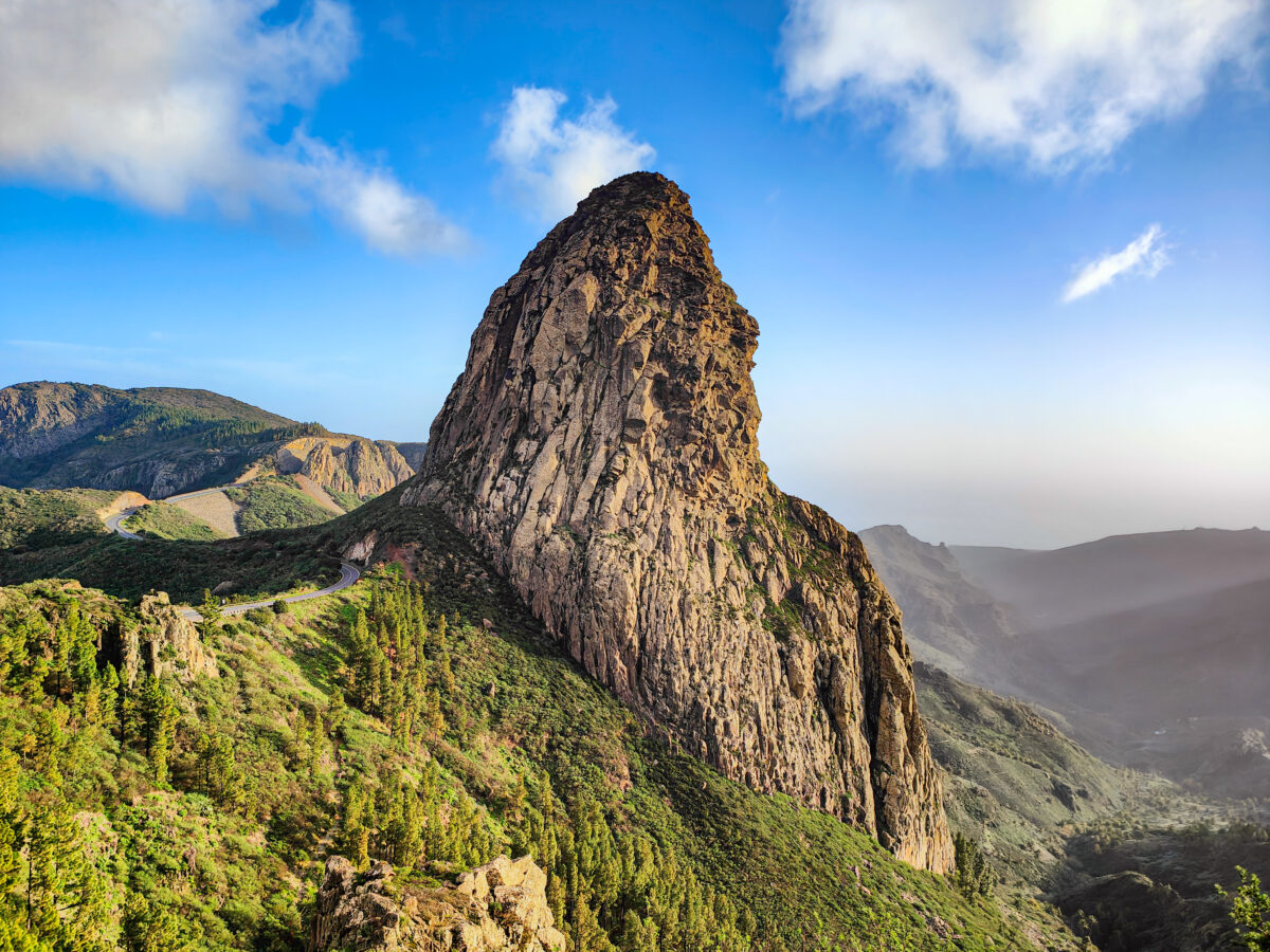 Mountain view of Roque de Agando rock tower. Beautiful landscape, forest and winding road. Natural landmark. Garajonay National Park, La Gomera, Canary Islands, Spain