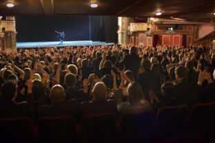 Audience applauding ballerina on stage in theater