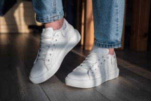 Closeup shot of a woman showing her white shoes in the room