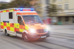 An emergency vehicle drives through the city with blue lights and high speed