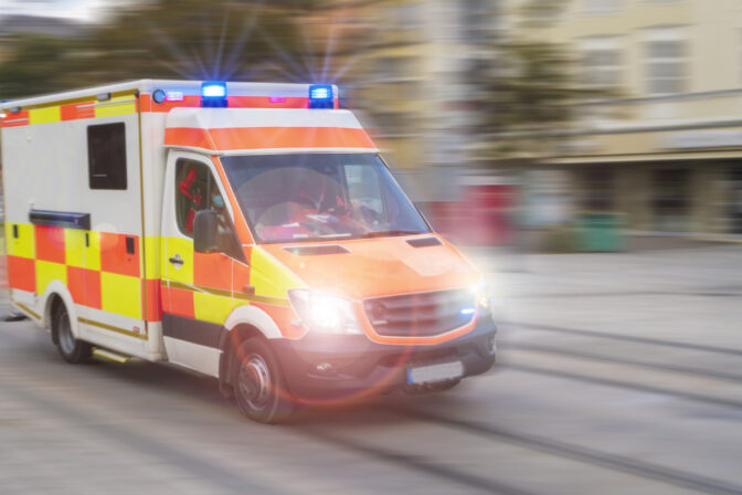 An emergency vehicle drives through the city with blue lights and high speed