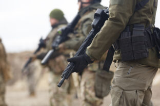 Group of Ukrainian soldiers equipped with modern assault rifles training at the shooting range. Military men armed with automatic machine guns practicing outdoor