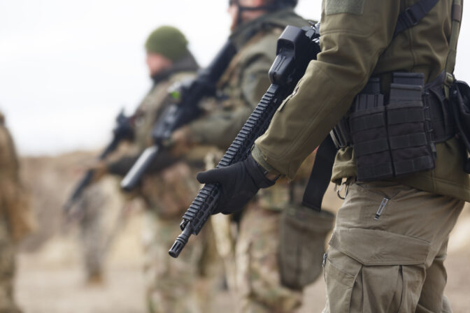 Group of Ukrainian soldiers equipped with modern assault rifles training at the shooting range. Military men armed with automatic machine guns practicing outdoor