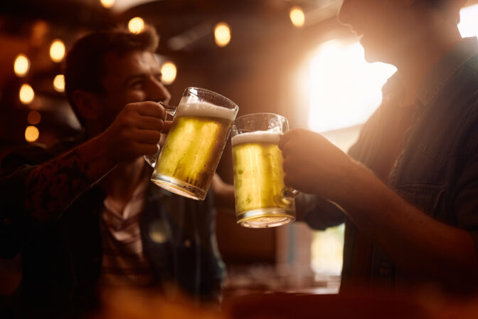 Close up of friends toasting with beer in a pub.
