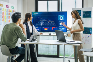 Asian worman leader presenting a financial data and strategies in a modern office with charts and graphs displayed on a large screen