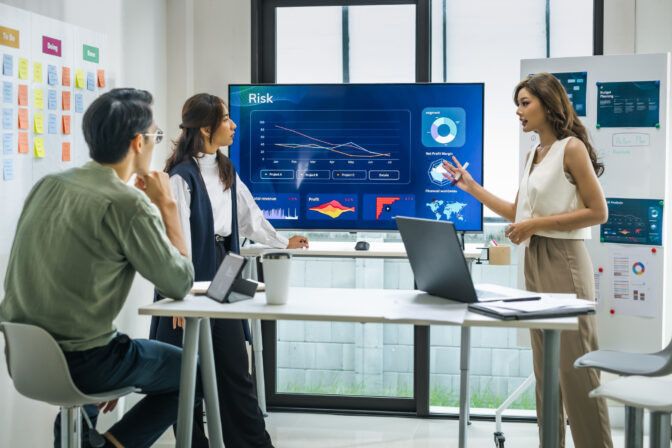 Asian worman leader presenting a financial data and strategies in a modern office with charts and graphs displayed on a large screen