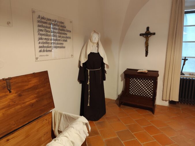 Kláštorná izba s figurínou rehoľnice, krížom a modlitebným pultom v Kláštornom múzeu.