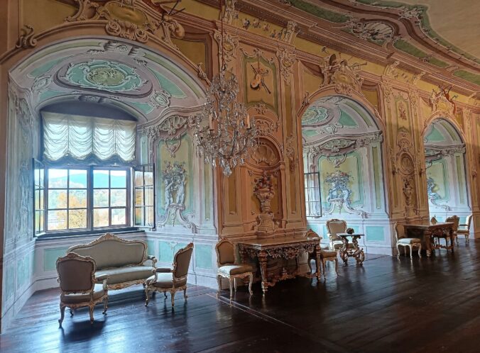Zrkadlová sála s rokokovou výzdobou a krištáľovými lustrami na zámku, kde sa odrážala noblesa aristokracie.